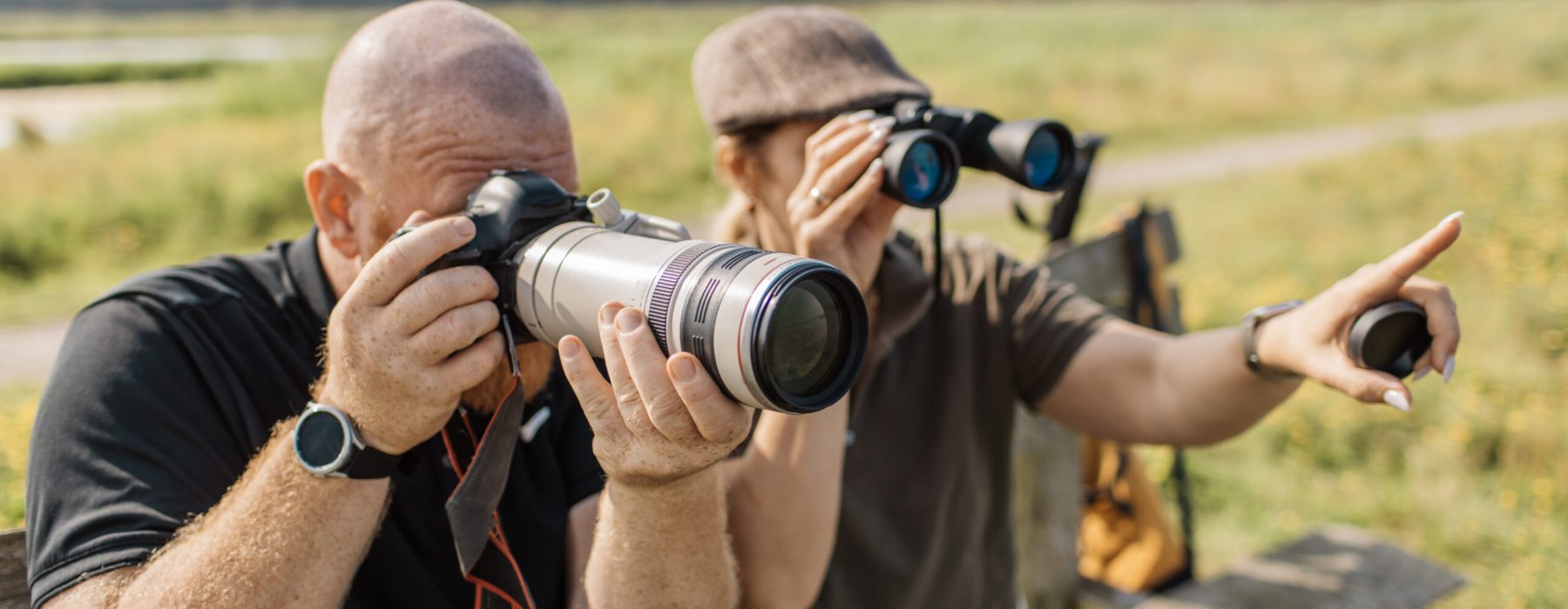 Active senior birdwatching couple made up of a beautiful blonde woman and a handsome redhead man enjoying a new hobby together in the Netherlands
